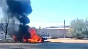 Vehículo envuelto en llamas desprendiendo una columna de humo negro al lado de un árbol seco en medio de calles de Michoacán