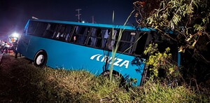 Camión de pasajeros color azul con la inscripción Aruza en un costado caída dentro de una zanja con árboles y maleza al lado de la carretera