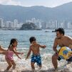 Familia disfrutando de las vacaciones de semana santa y jugando frente al mar de Acapulco con una pelota en un día soleado.