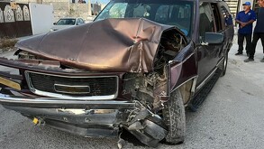 Se observa una camioneta negra con gris destrozada del frente y unos hombres parados al fondo.