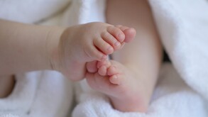 Se observan los pies de un bebé de meses en un fondo blanco.