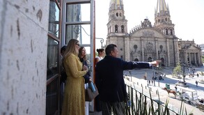 Gobernador de Jalisco, Pablo Lemus Navarro, apuntando con el dedo en un balcón con vista a la Catedral de Guadalajara con mujeres detrás de él