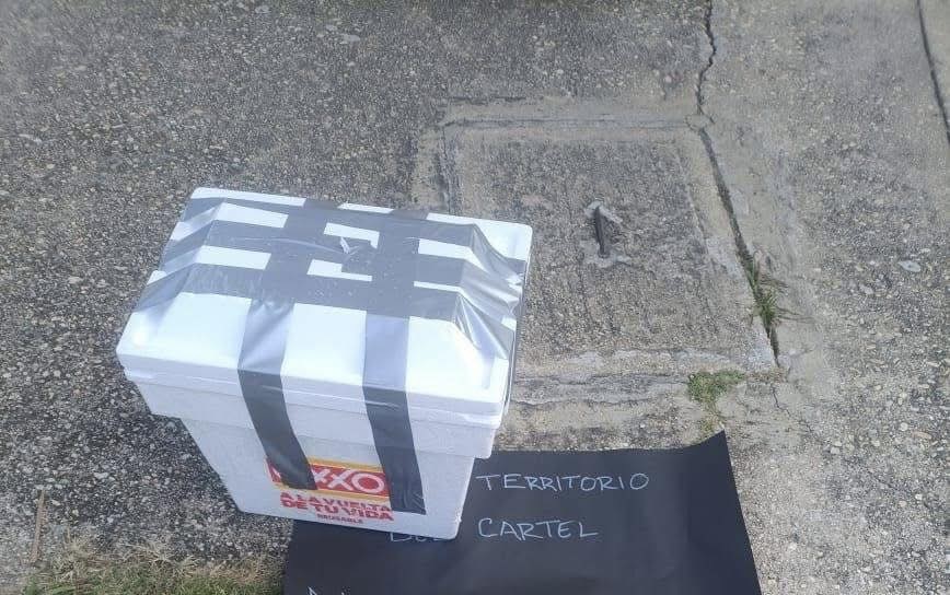 Hielera atada con cinta junto a un mensaje del crimen organizado en Veracruz.