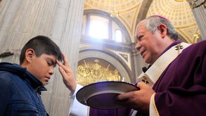 un sacerdote coloca ceniza en la frente de un joven durante el miércoles de ceniza