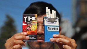 un hombre sostiene cajetillas de cigarros frente a su rostro