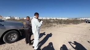 Se observa a dos personas con uniforme blanco en un terreno baldío.