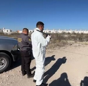 Se observa a dos personas con uniforme blanco en un terreno baldío.