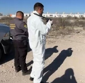 Se observa a dos personas con uniforme blanco en un terreno baldío.