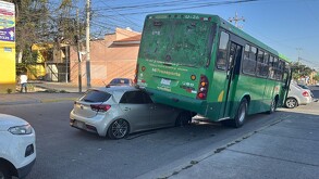 Auto compacto color gris incrustado debajo del lado de la llanta izquierda trasera de un camión de la ruta 26 de Guadalajara ladeado sobre un costado