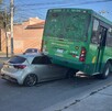 Auto compacto color gris incrustado debajo del lado de la llanta izquierda trasera de un camión de la ruta 26 de Guadalajara ladeado sobre un costado