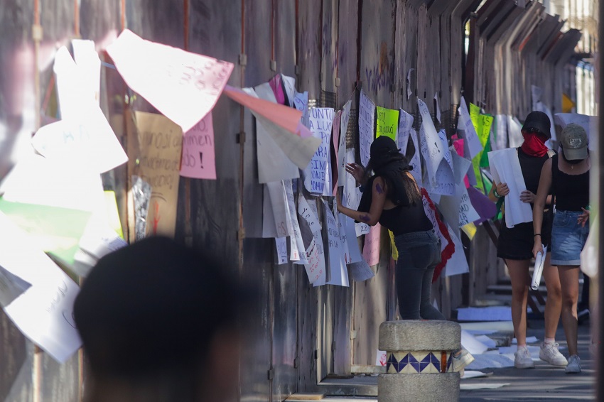 Mujeres protestan junto a una barda que cubre el Ayuntamiento de Puebla.