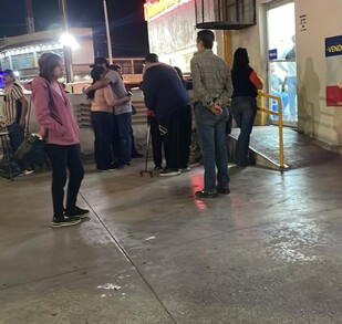 Se observa a varias personas abrazadas afuera de un establecimiento.