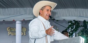 Carlos Manzo hablando por un micrófono delante de un podio durante una presentación pública en Uruapan