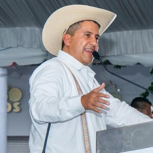 Carlos Manzo hablando por un micrófono delante de un podio durante una presentación pública en Uruapan