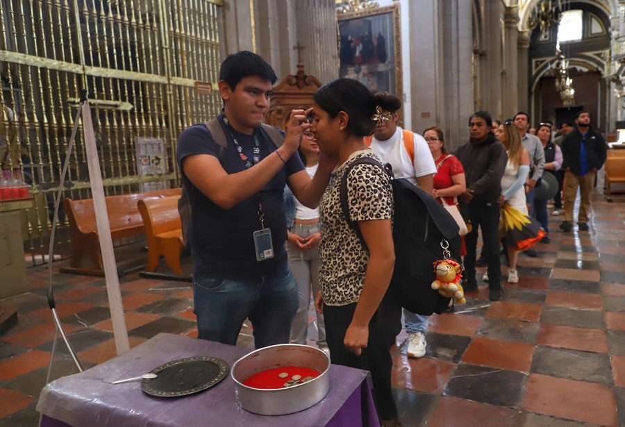 Jóvenes toman ceniza para ponerla en su frente por el Miércoles de Ceniza 2026 en Puebla.