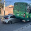 Auto compacto color gris incrustado debajo del lado de la llanta izquierda trasera de un camión de la ruta 26 de Guadalajara ladeado sobre un costado