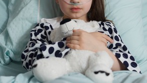Niña hospitalizada sujetando un oso de peluche.