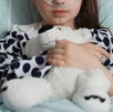Niña hospitalizada sujetando un oso de peluche.