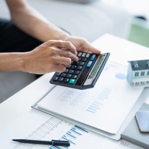 Una persona realizando operaciones con una calculadora y una computadora portátil