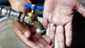 Válvula de agua con dos manos con las palmas extendidas y una cubeta debajo levemente desenfocadas