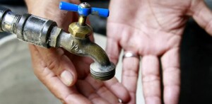 Válvula de agua con dos manos con las palmas extendidas y una cubeta debajo levemente desenfocadas