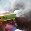 Persona sacando humo mientras utiliza un vapeador.