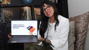 Mujer sonriendo mientras sostiene una computadora portátil con las manos.