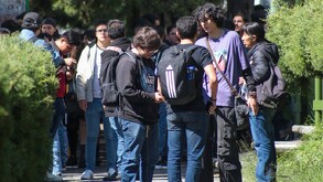 Se observan a varios jóvenes cargando mochilas, y a una señora entre la multitud.
