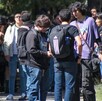 Se observan a varios jóvenes cargando mochilas, y a una señora entre la multitud.