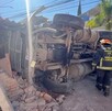 Camión de volteo volcado sobre la pared de una casa con oficiales de Protección Civil y Bomberos de Tlaquepaque a un lado