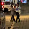 Mujer y niño cruzan la calle junto a una patrulla de policía.