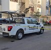Patrulla de la Policía de Tlajomulco sosteniendo una cinta policiaca que acordona la calle afuera de edificios de departamentos con autos alrededor