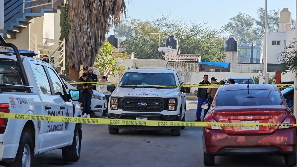 Camioneta del Instituto Jalisciense de Ciencias Forenses frente a una patrulla de la Policía de Tlajomulco con cintas amarillas acordonando una calle