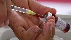 Manos sosteniendo jeringa y vacuna contra el sarampión