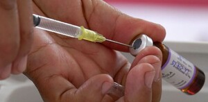 Manos sosteniendo jeringa y vacuna contra el sarampión