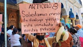 Una anciana sostiene un cartel durante una protesta en contra del incremento en el costo del agua.