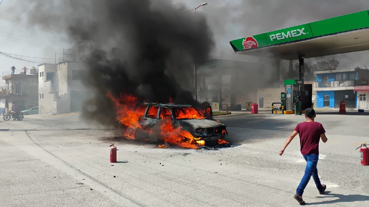 Automóvil envuelto en llamas frente a una gasolinera de Pemex con un hombre caminando a un lado