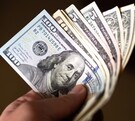 Persona sujetando dólares estadounidenses.