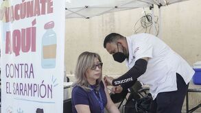 Mujer es vacunada por un enfermero en un centro de vacunación contra el sarampión.