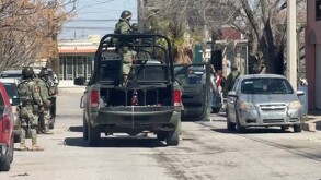 Se observan a varios hombres vestidos de militares, algunos arriba de camionetas.