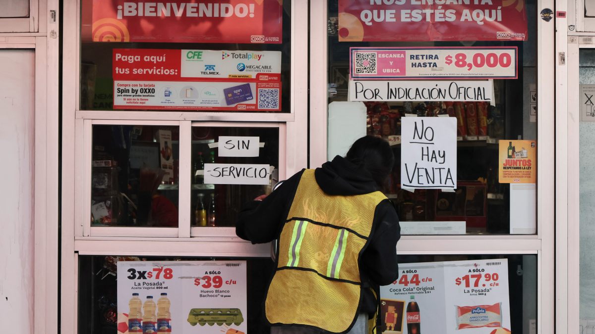 un hombre se asoma a la puerta de una tienda oxxo en puebla