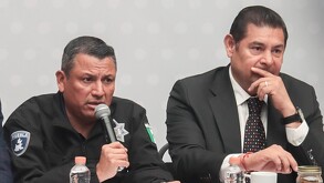 Dos hombres sentados frente a una mesa para una rueda de prensa.