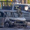 Militares parados junto a un auto calcinado en calles de Jalisco.