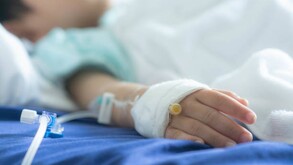 Niño acostado en una cama de hospital con un catéter intravenoso y una venda colocados en su mano