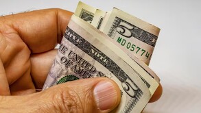 Persona sujetando dólares estadounidenses.