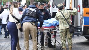 Una alumna es trasladada en una camilla hacia una ambulancia para recibir atención médica.