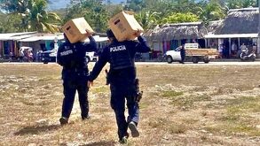 Personas con uniforme policial cargando cartones de cerveza.
