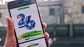 Mano sosteniendo un teléfono celular con la leyenda de Admisión BUAP 2026.