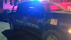 Vista del costado de una patrulla de la Policía del Estado de Jalisco con la sirena encendida durante la noche