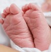 Se observan los pies de un recién nacido, tapado con una cobija.